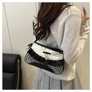 Close-up of black and white bow shoulder bag with heart pattern and lace trim