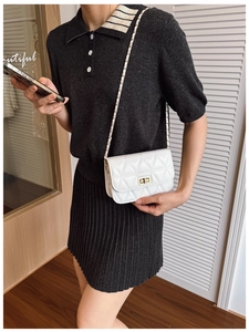 Close-up of white quilted crossbody bag with gold chain strap worn by a model