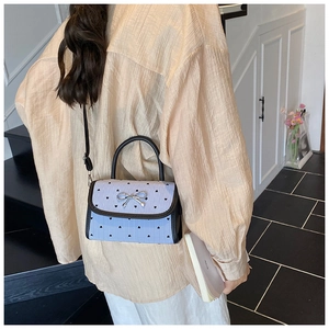 Detailed view of light blue crossbody bag with bow buckle and heart stripe pattern