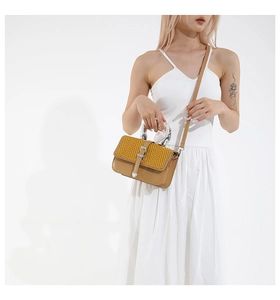 Detail of color-block bag with herringbone texture, leather body and silver metal handle
