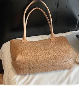 Close-up of the intricate intrecciato leather weaving and double handles on a tote bag
