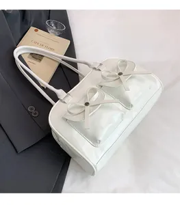 White faux leather shoulder bag with decorative bows and silver studs on front pockets