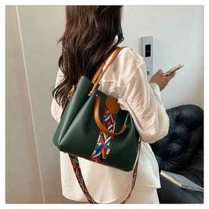 Detail of dark green tote bag with bohemian woven strap and round brown handle