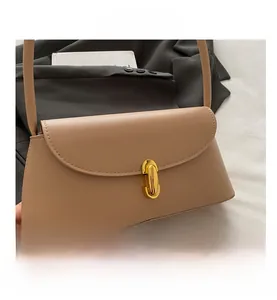 Detail shot of a beige minimalist shoulder bag with a gold oval twist lock closure