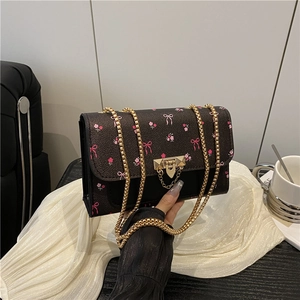 Retro brown crossbody bag with pink floral and bow patterns featuring a gold chain strap