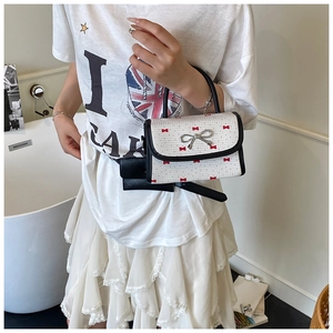 Detail of white mini crossbody bag with red bow prints and silver metallic bow clasp