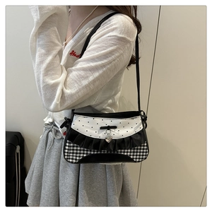 Detail of checkered shoulder bag with ruffles, bow, and silver heart pendant