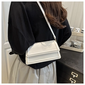 Back view of a model wearing a white PU leather crossbody bag with a sleek flap design