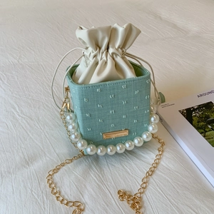 Borsa a secchiello verde pastello intrecciata con manico di perle e ricami floreali