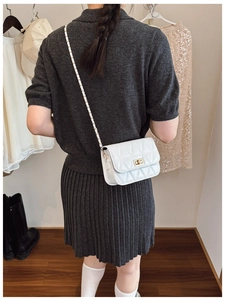 Sac bandoulière blanc matelassé avec fermoir doré porté par un mannequin chic