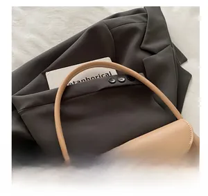 Close-up of beige leather shoulder bag with golden metal buckle and rounded handle