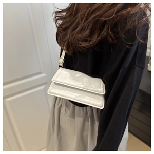 White glossy patent leather rectangular shoulder bag shown on model with gold hardware
