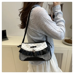 Detail of lace frill baguette bag with heart pendant and monochrome check pattern