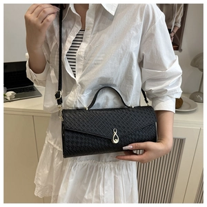 Detail of black crocodile texture shoulder bag with gold teardrop clasp and strap