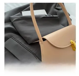 Close-up of beige leather shoulder bag with gold metallic twist lock on grey blazer