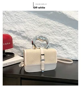 Detail of cream white handbag featuring woven straw flap and modern silver metal handle
