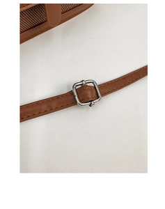 Detail of adjustable silver buckle and caramel leather strap on a woven crossbody bag