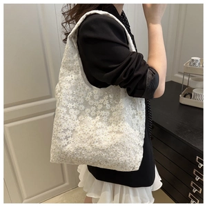 Gros plan détaillé sur la broderie en dentelle florale blanche du sac cabas en toile