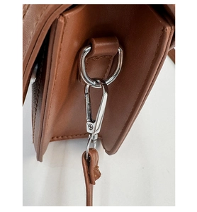Detail of silver D-ring and lobster clasp on brown leather shoulder bag strap