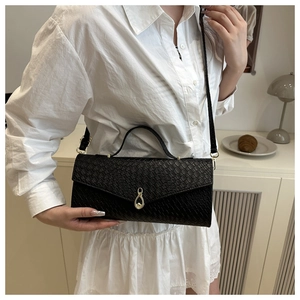 Detail of black faux crocodile skin shoulder bag with gold teardrop-shaped twist lock