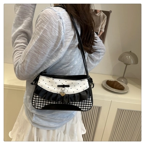 Detail of checkered shoulder bag featuring black ruffles and heart-shaped metal pendant