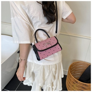 Polka dot bow bag with pink stripes and heart patterns worn by model on shoulder