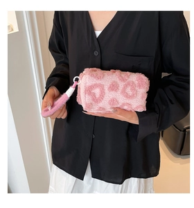 Detalle del neceser de felpa rosa con diseño de corazones y correa de muñeca suave