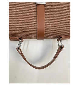 Detail of vintage brown woven fabric, leather handle and silver metal D-ring hardware