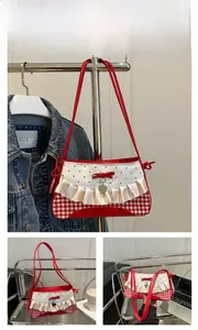 Detail of red and white checkered underarm bag with ruffle trim and heart pendant