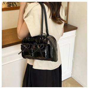 Detail of black glossy PU leather tote bag with decorative bows and front pockets