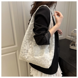 Détail du sac cabas en dentelle blanche avec broderie florale et grande bandoulière