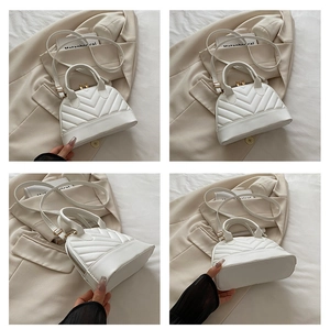 Close-up of white quilted shell bag with gold hardware and detailed V-stitch patterns