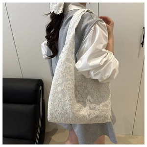 Détail de la broderie en dentelle florale sur un sac fourre-tout d'été blanc crème