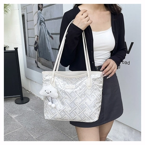 Detail of white tote bag with grey geometric patterns and a plush cloud charm accessory