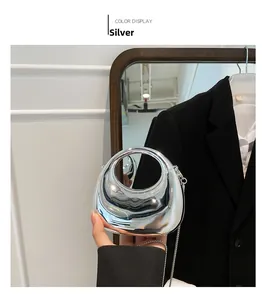 Detail of silver mirror mini clutch bag with polished finish and metal chain strap