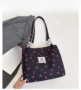 Detail of cherry print canvas tote bag with metal chain strap and logo patch