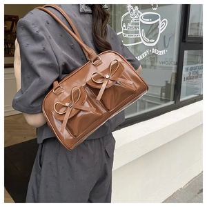 Detail of dark brown tote bag with bow accents and dual flap pockets in cafe setting