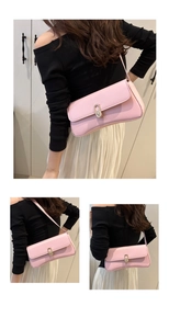 Détail d'un sac sous le bras en cuir rose clair avec un fermoir en métal doré ovale