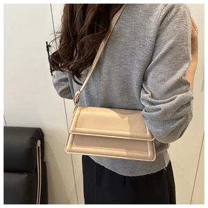 Detail of minimalist cream crossbody bag with wide rectangular quilting on model