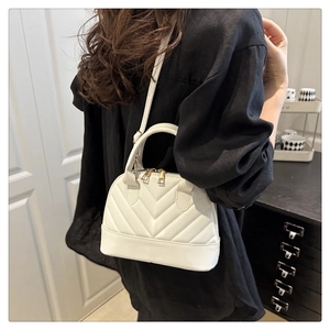 Detail of white V-quilted leather shell bag with adjustable strap and gold zipper