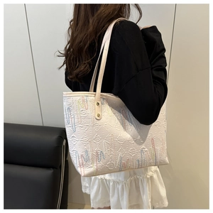 Detailed side view of beige canvas tote bag with colorful wave embroidery worn by model