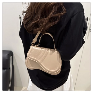 Side view of beige crossbody bag showing its unique wavy flap and leather texture