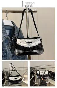 Close-up of black and white bow shoulder bag with heart pendant and gingham pattern