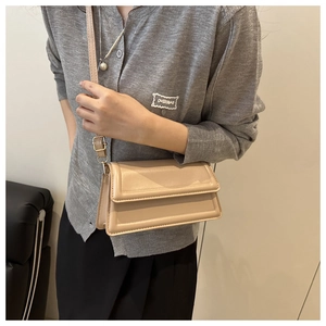 Detail view of beige square crossbody bag with fine stitching and golden metal hardware