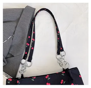 Detail of cherry print tote bag featuring fabric handle with silver metal chain rings