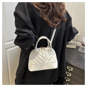 Detail of white quilted shell handbag with dual top handles and gold-tone double zippers