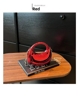 Detail of red crescent acrylic evening bag with gold chain and circular handle