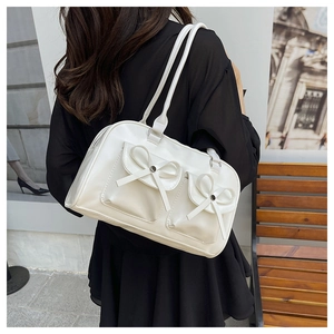 Close-up of white canvas shoulder bag featuring double pockets and decorative bows