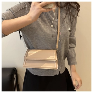 On-body view of beige crossbody bag with horizontal stitching and slim leather strap
