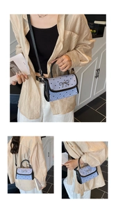 Detail of light purple bag with black heart prints and silver metal bow clasp